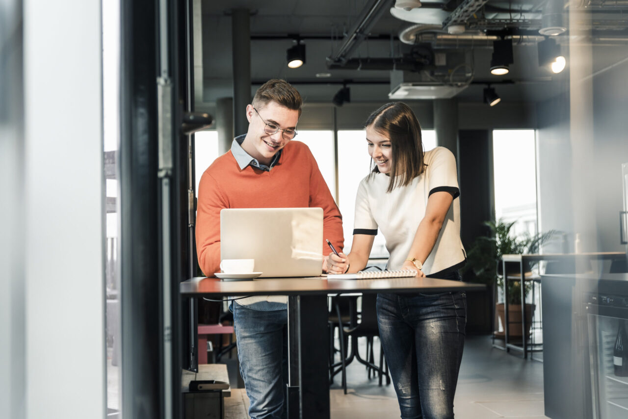 Casual businessman and woman with laptop meeting in office