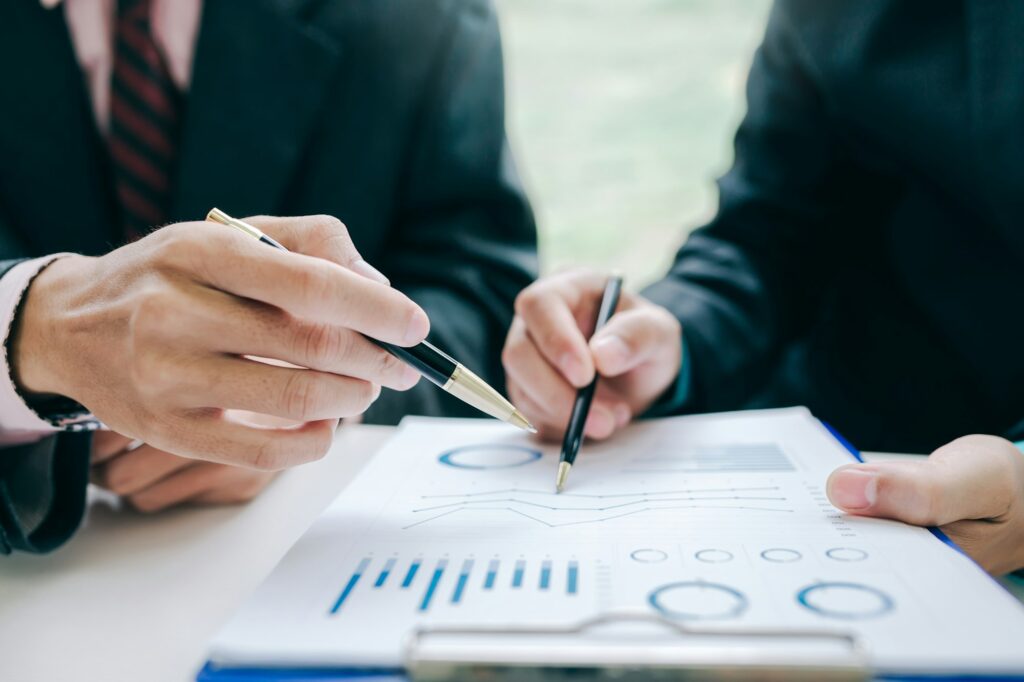 Businessman holding pen pointing to graph data to show investors see growth in business investment.