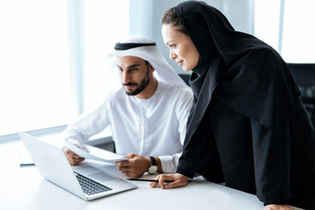 Handsome man and woman with traditional clothes working in an office of Dubai