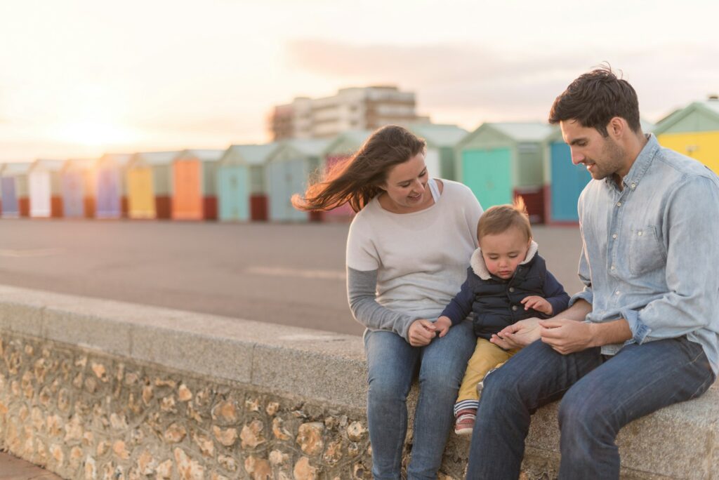 Young family sitting on beach wall