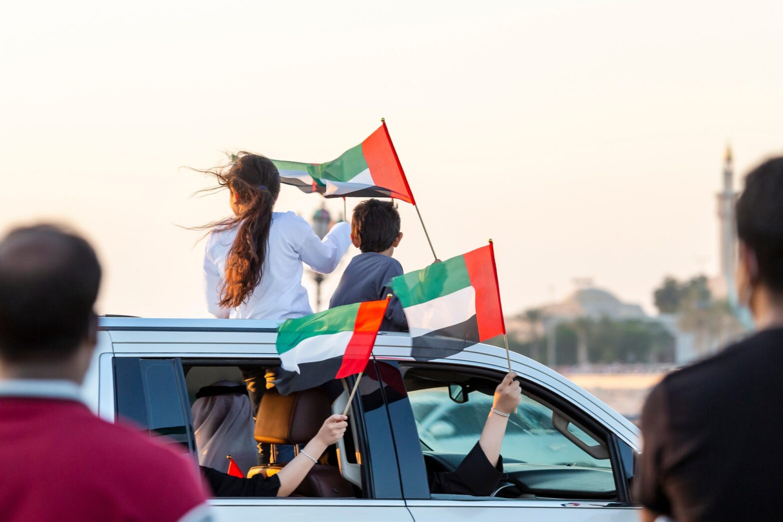 Family celebrating 50th UAE National Day on Corniche. Children with UAE flags.
